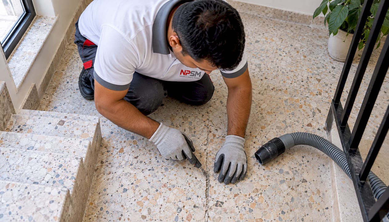 Technician cleaning a crack in terrazzo flooring